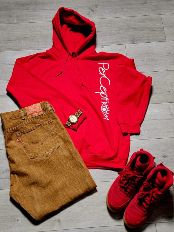 A red hoodie and brown shorts are on the floor.